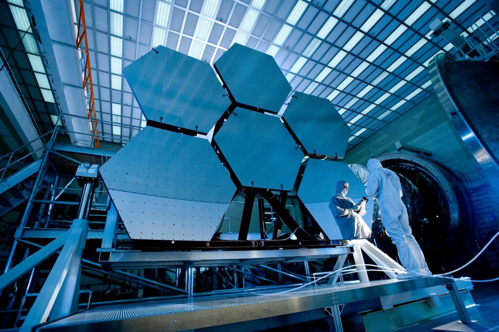pexels-photo-256381-256381 Engineers in protective suits work on telescopic mirrors in a high-tech lab.
