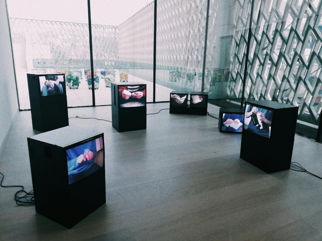 pexels-photo-4412789-4412789 Explore a modern art exhibit with multiple screens displaying digital art in a sleek museum setting.